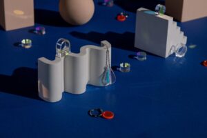 Artistic arrangement of jewelry on vibrant blue background with geometric shapes.
